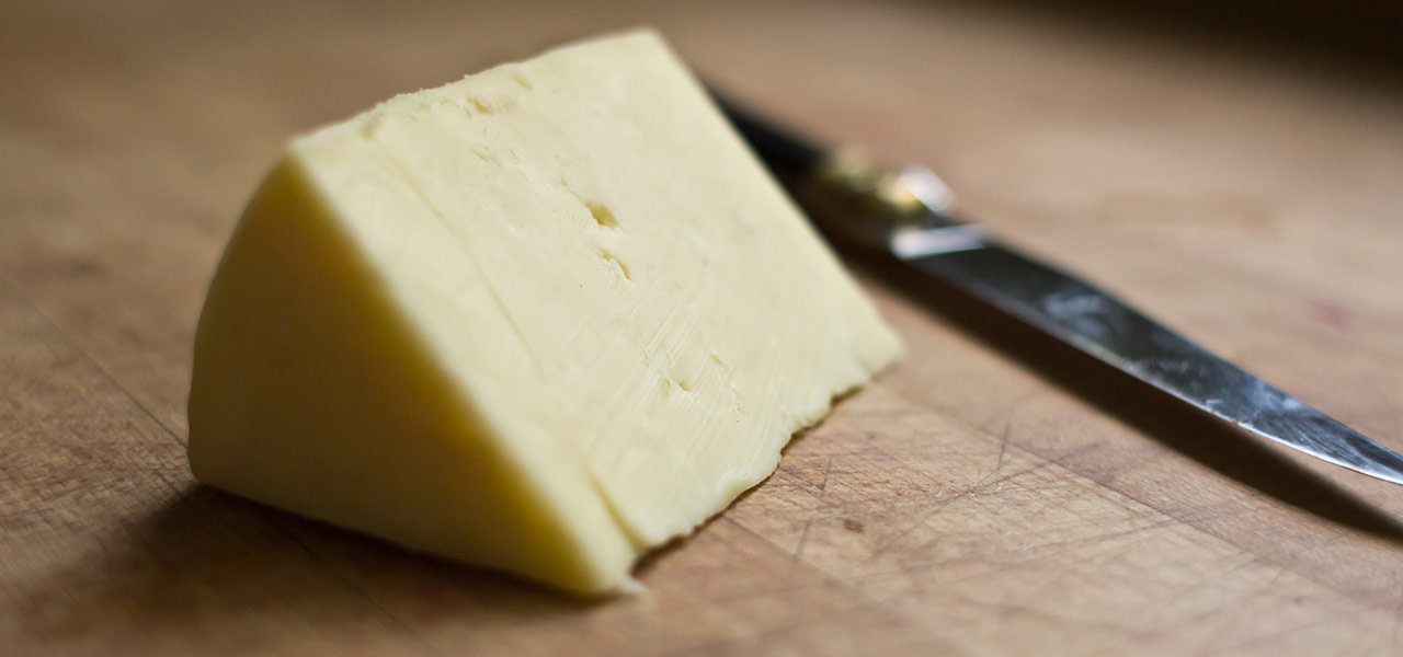 traditional farmhouse cheddar cheese on a cheese board with a knife
